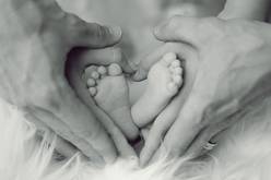Eltern umranden Babyfüße als Herzform